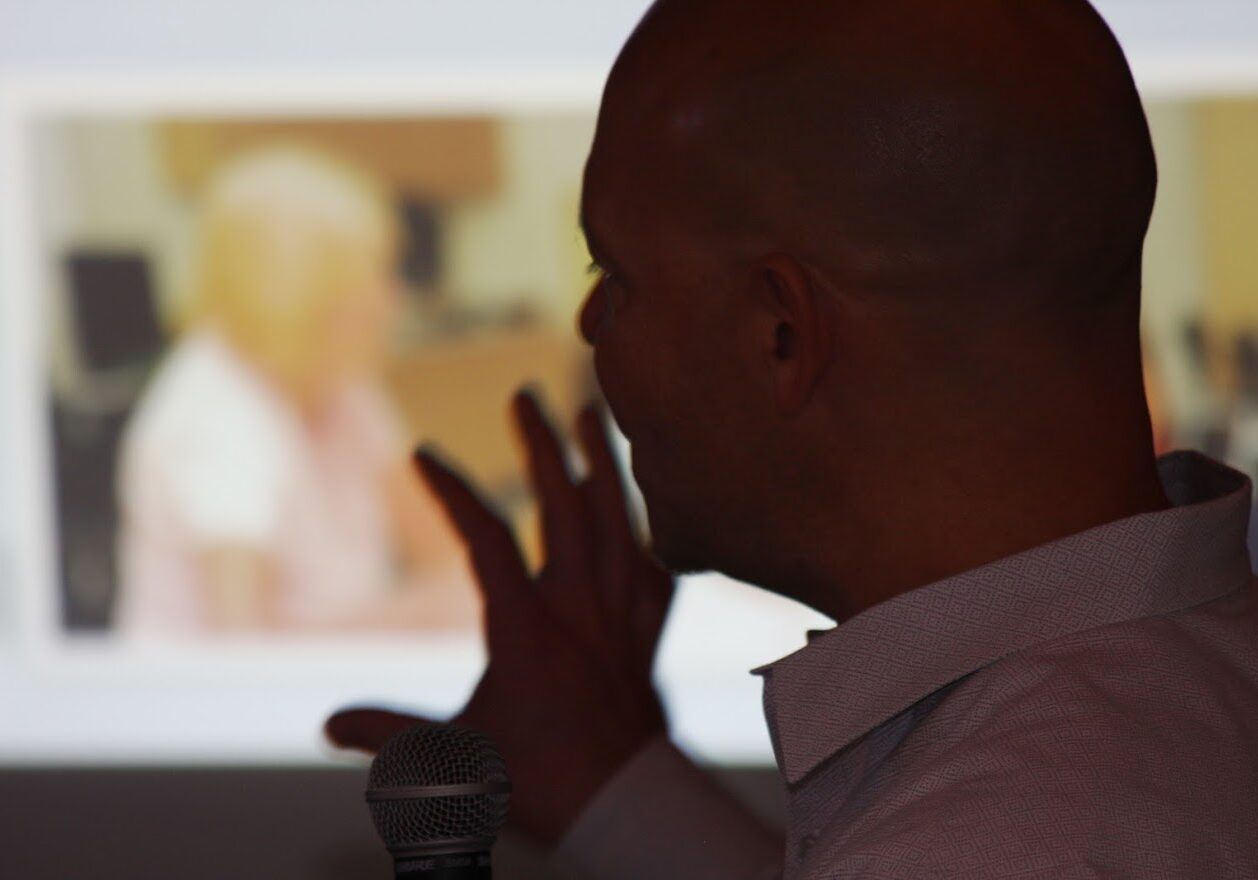 Presenter silhouette with microphone pointing at projection